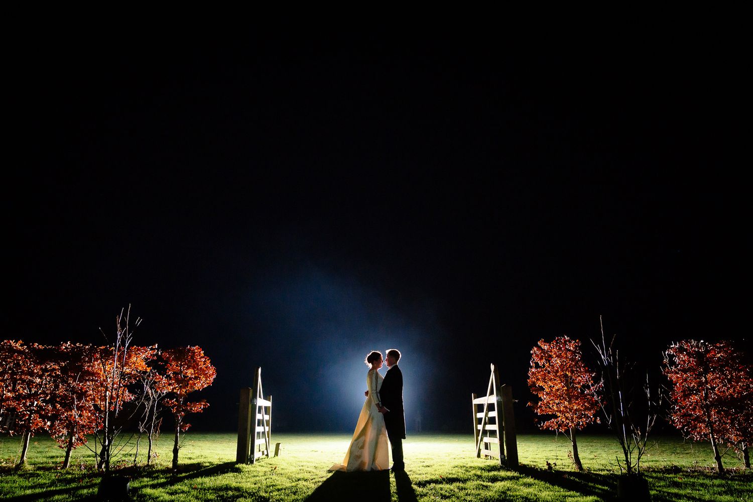 Artistic nighttime wedding photography using dramatic lighting and silhouettes against dark skies. Ellingham Hall