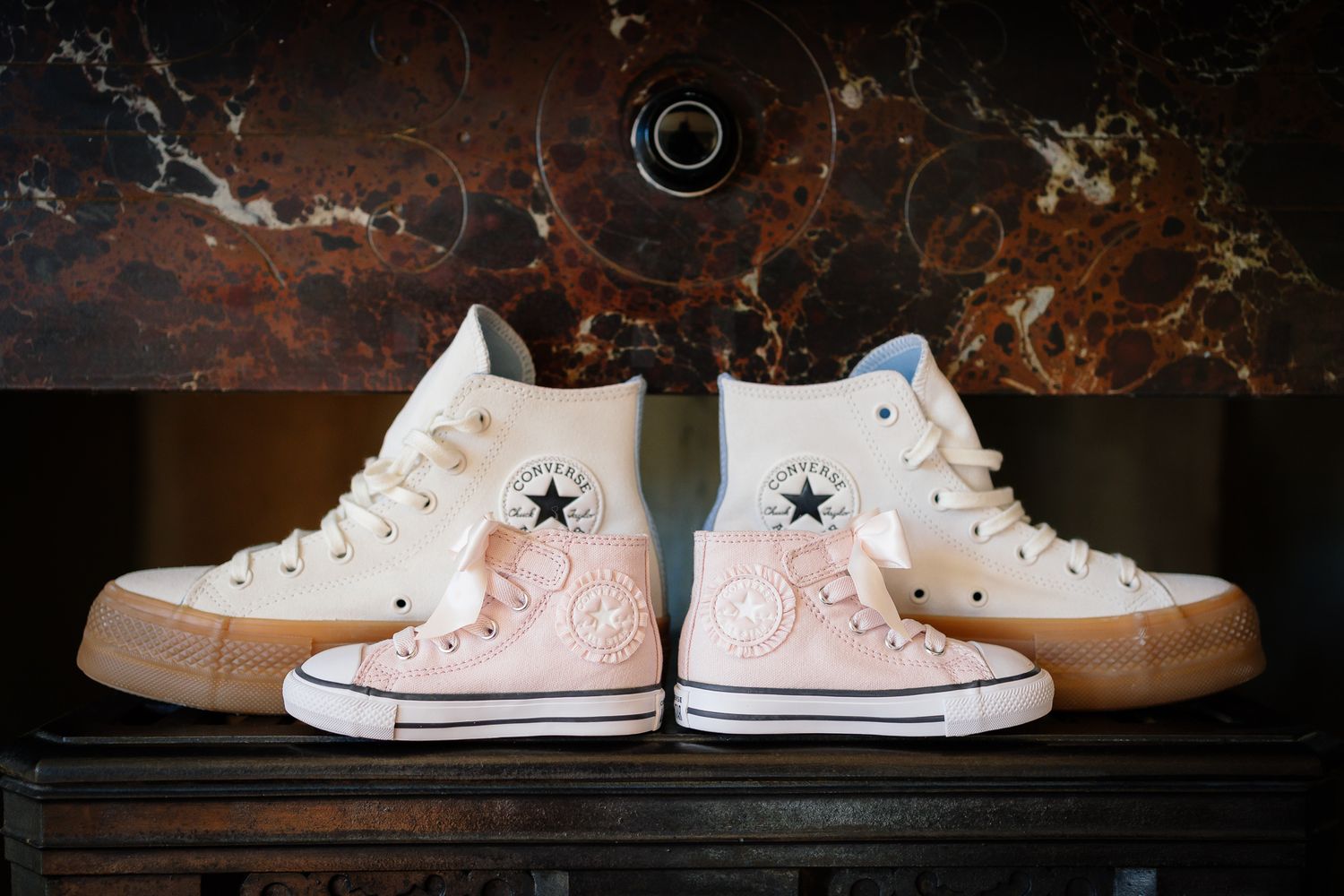 White decorated wedding sneakers arranged on dark wooden surface.