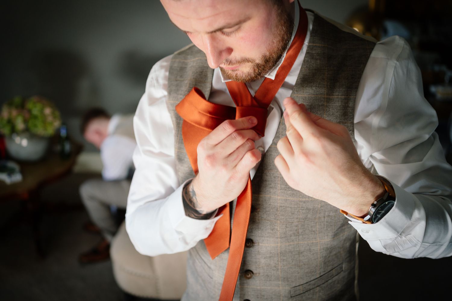 Series of shots showing someone adjusting an orange tie with white dress shirt.
