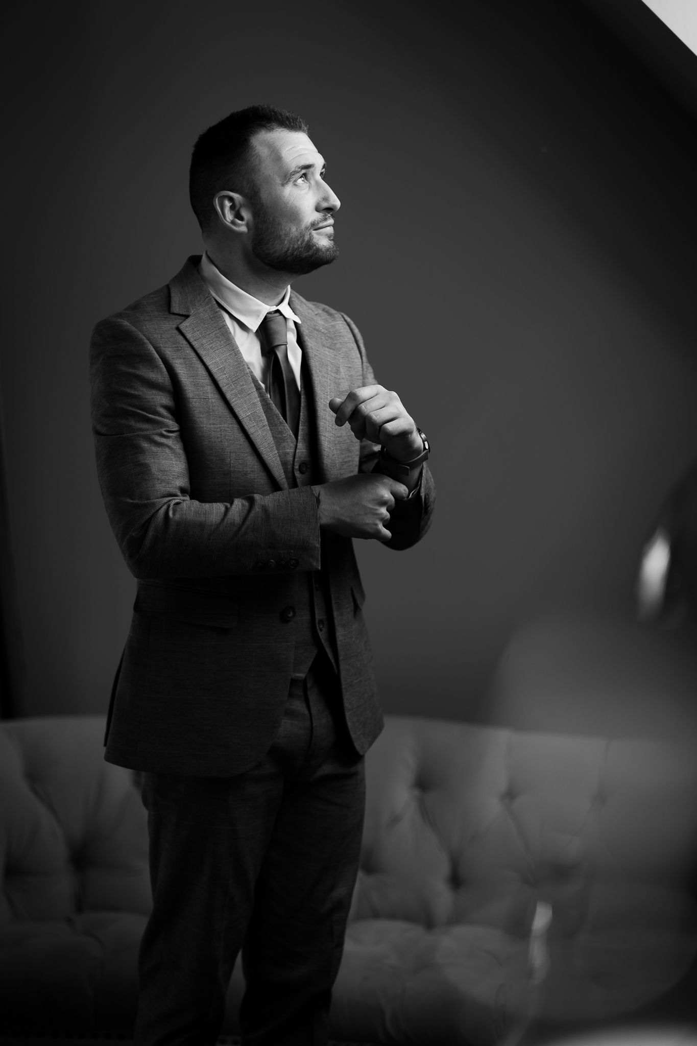 Dramatic black and white portraits of person in suit against dark background.