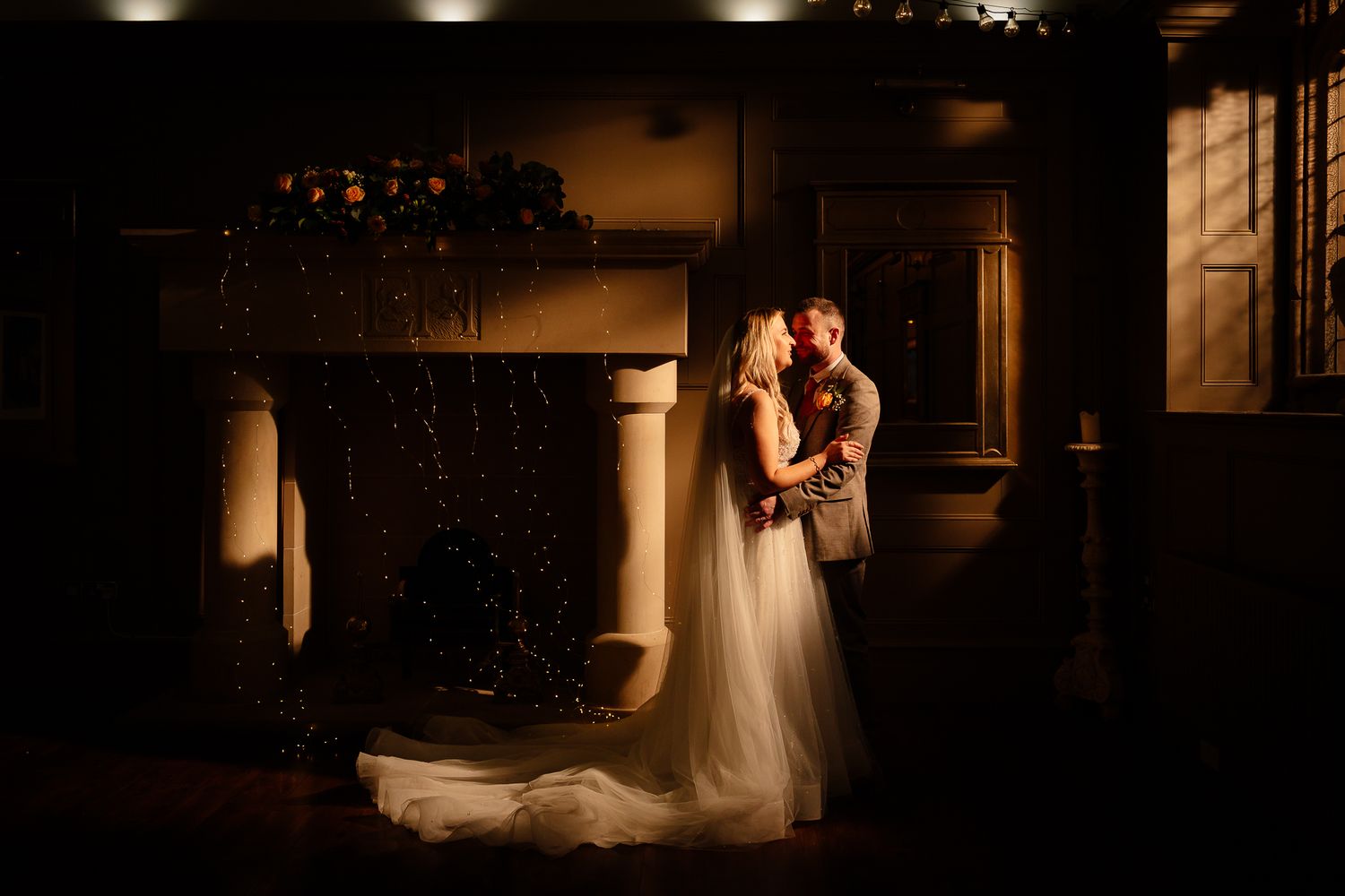 Dramatic low-light silhouettes of couple in romantic wedding venue setting.