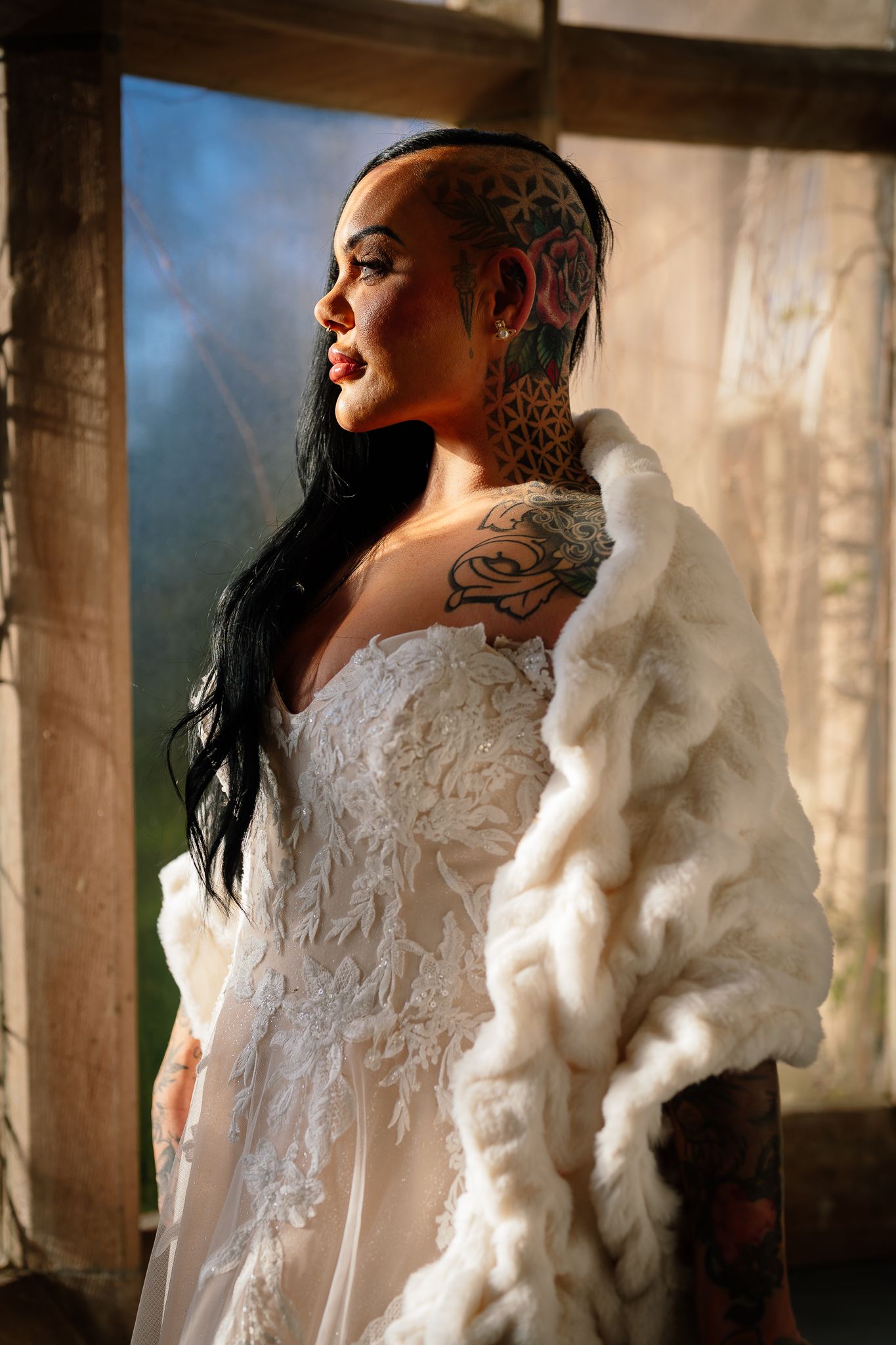 Artistic bridal portrait showing an elegant white lace gown and dramatic lighting in an architectural setting.