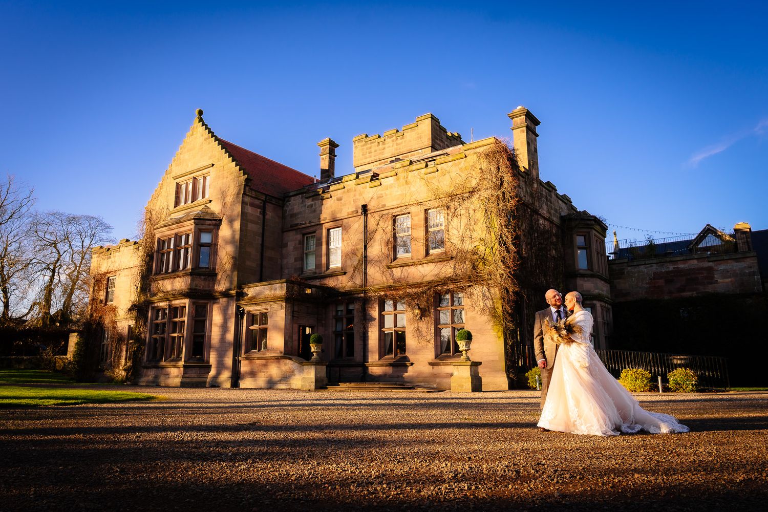 Panoramic wedding photos at historic stone building under bright blue sky.