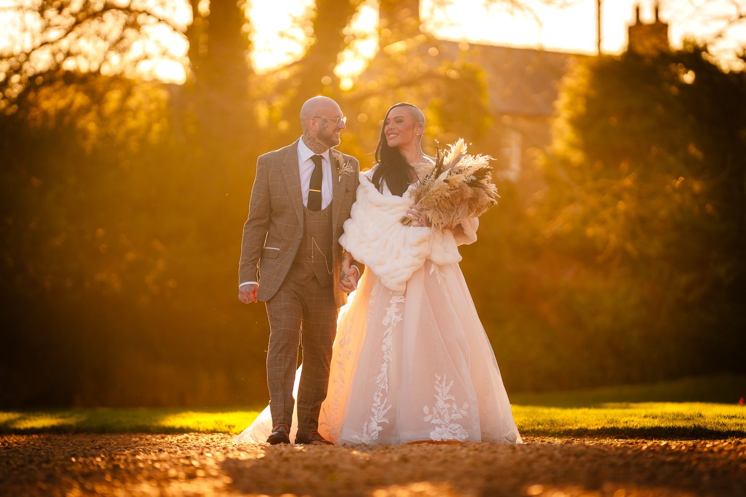 Wedding couple silhouetted against dramatic golden sunset in outdoor setting.