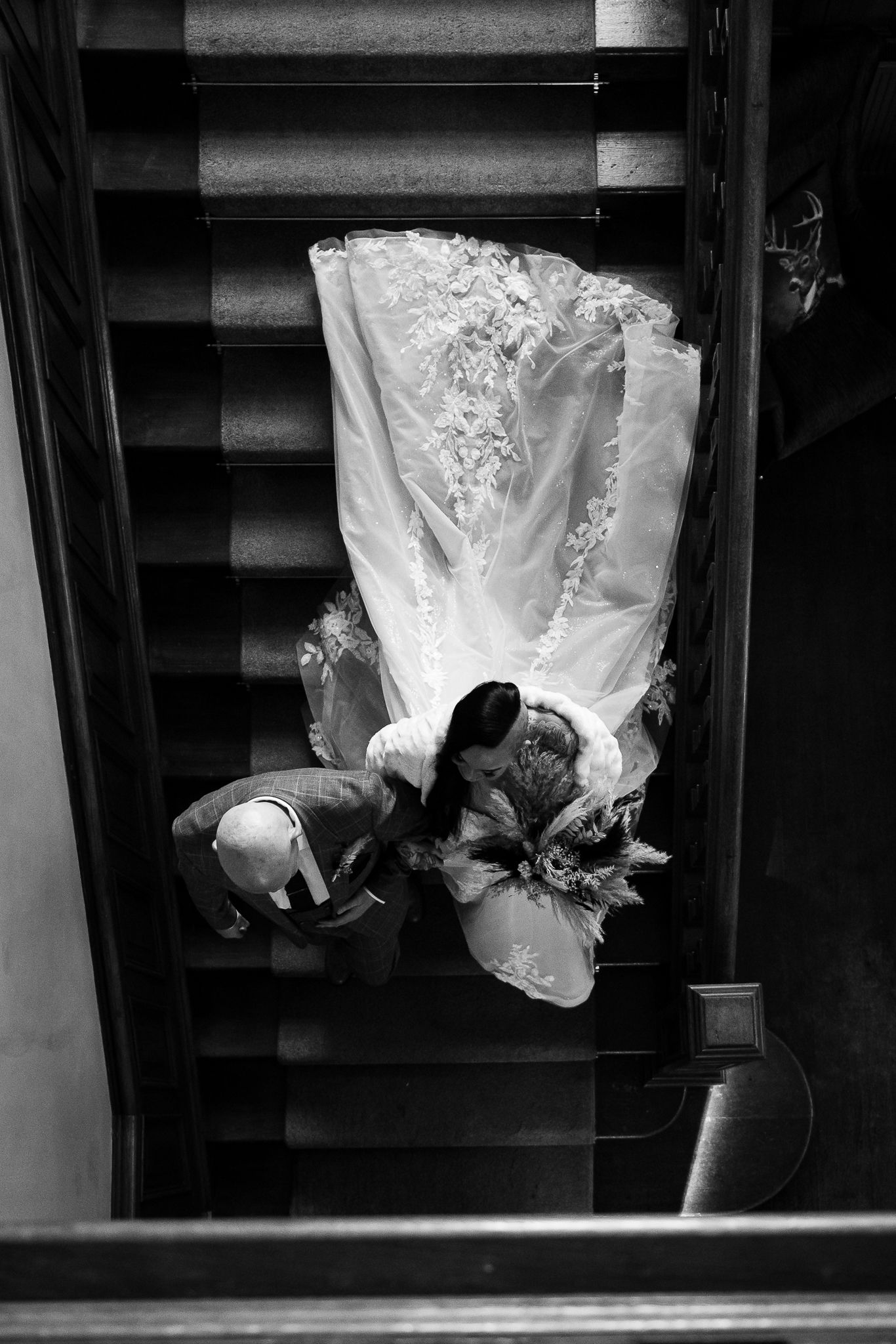Black and white artistic view of a wedding dress flowing down stairs. Ellingham Hall