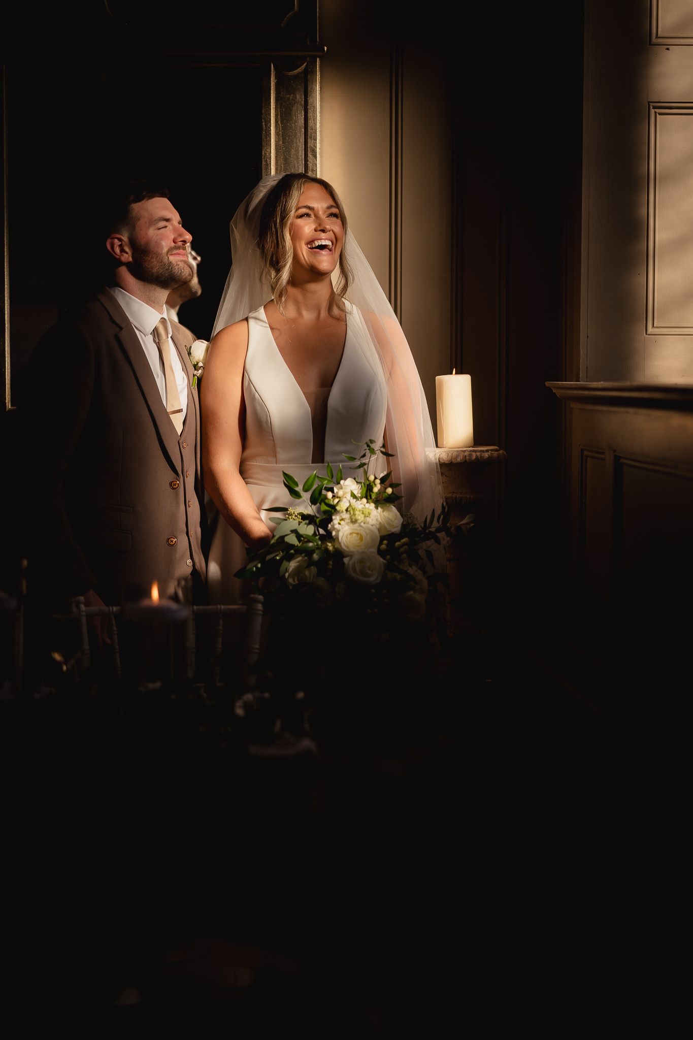 Dramatic window lighting creates intimate atmosphere during wedding moments.