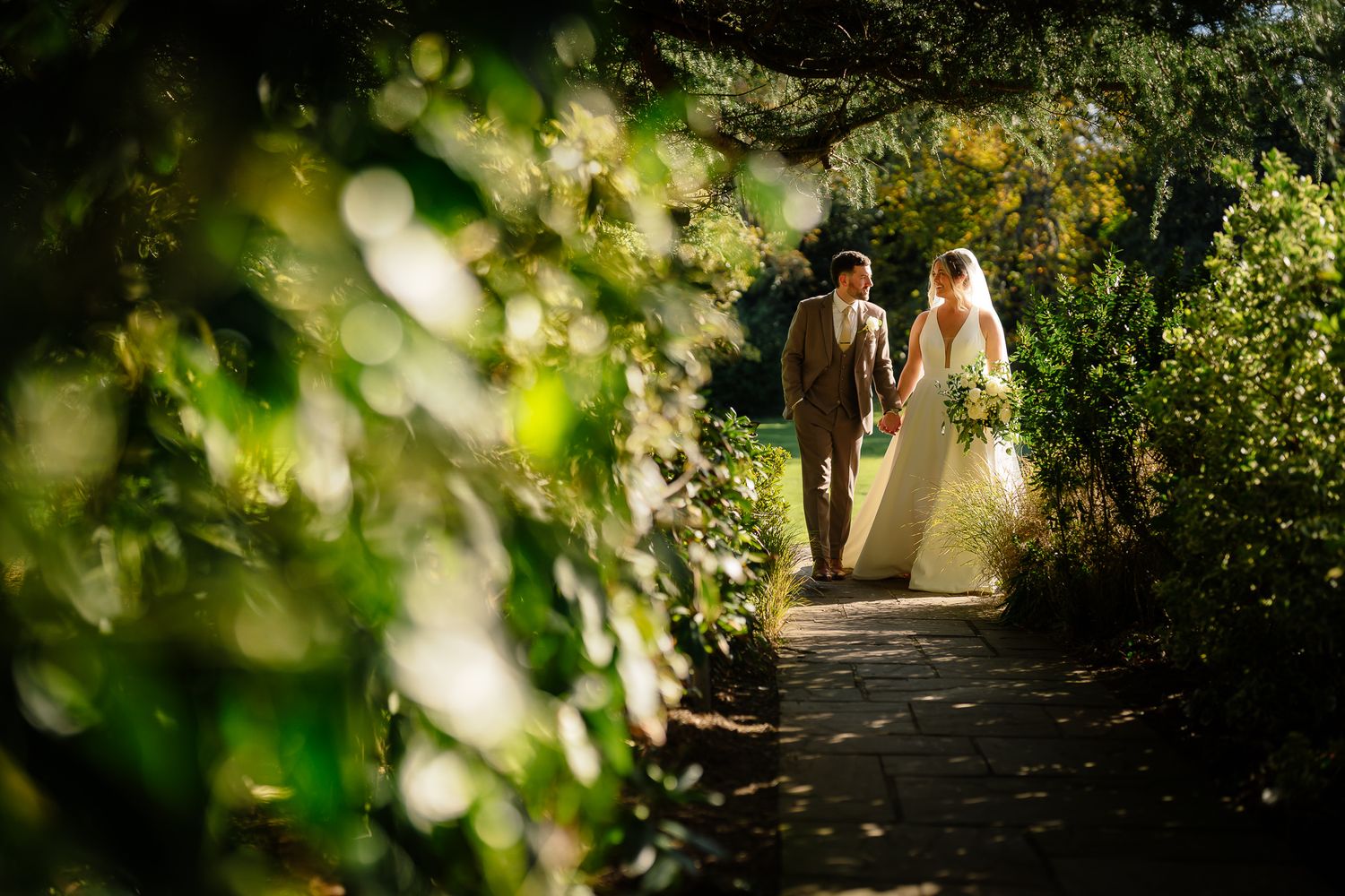 Garden pathway framed by lush greenery and natural bokeh lighting effects.