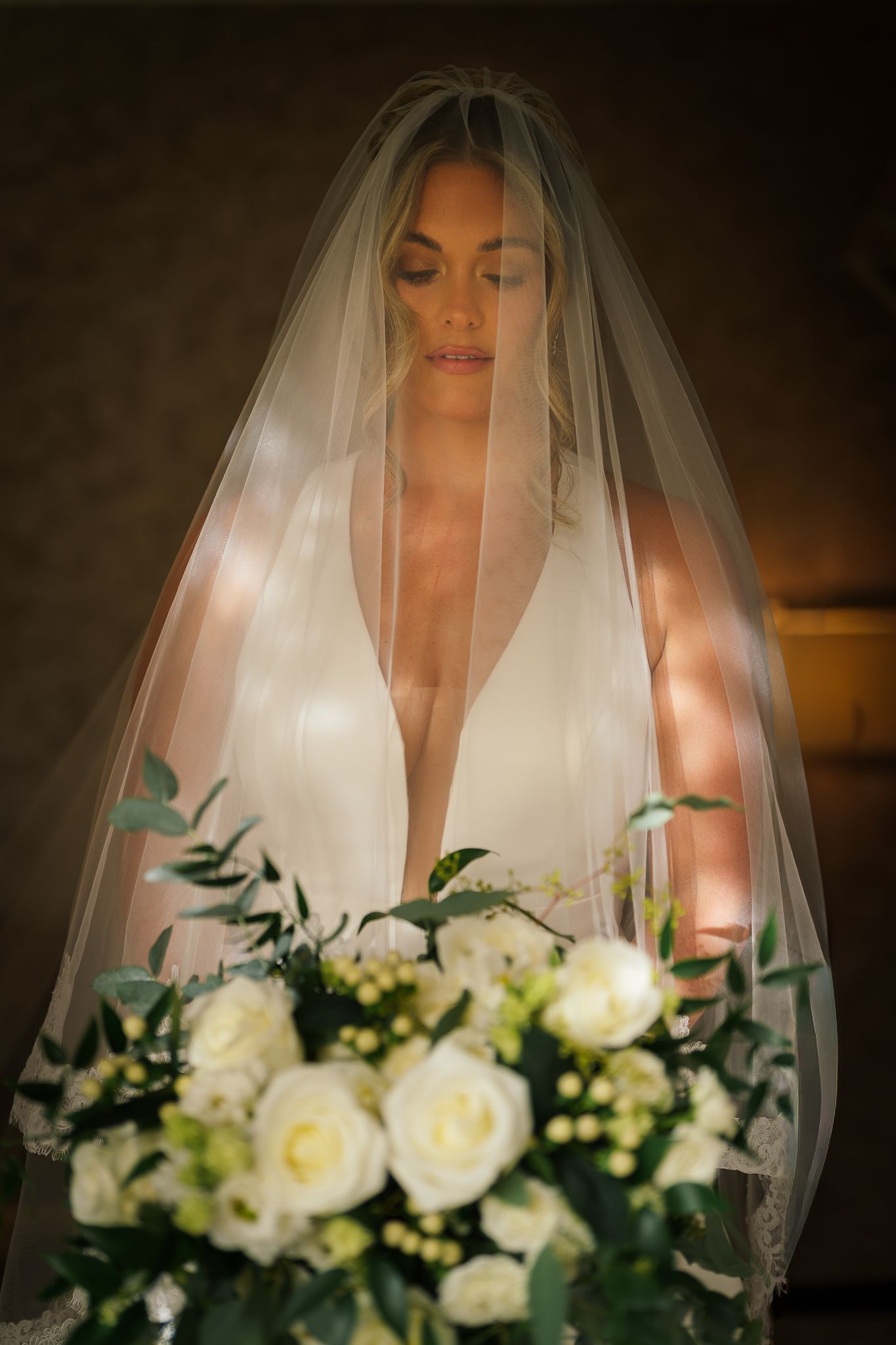 Close-up portrait shots of a bride in white veil holding a classic white and green wedding bouquet.
