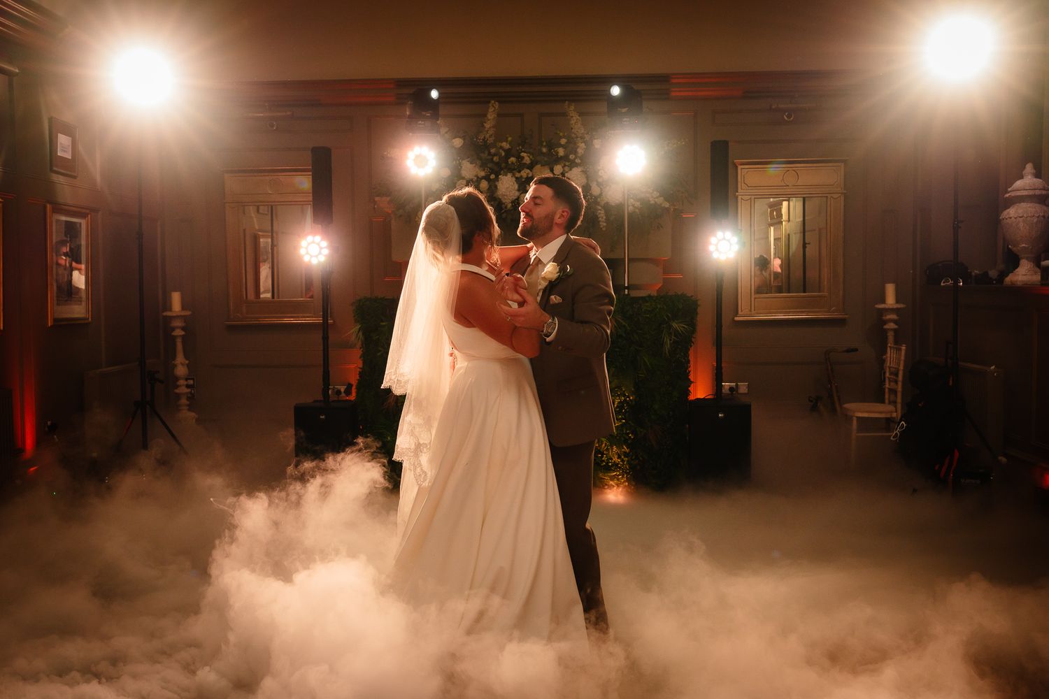 Couple shares romantic first dance surrounded by atmospheric fog and warm lighting.