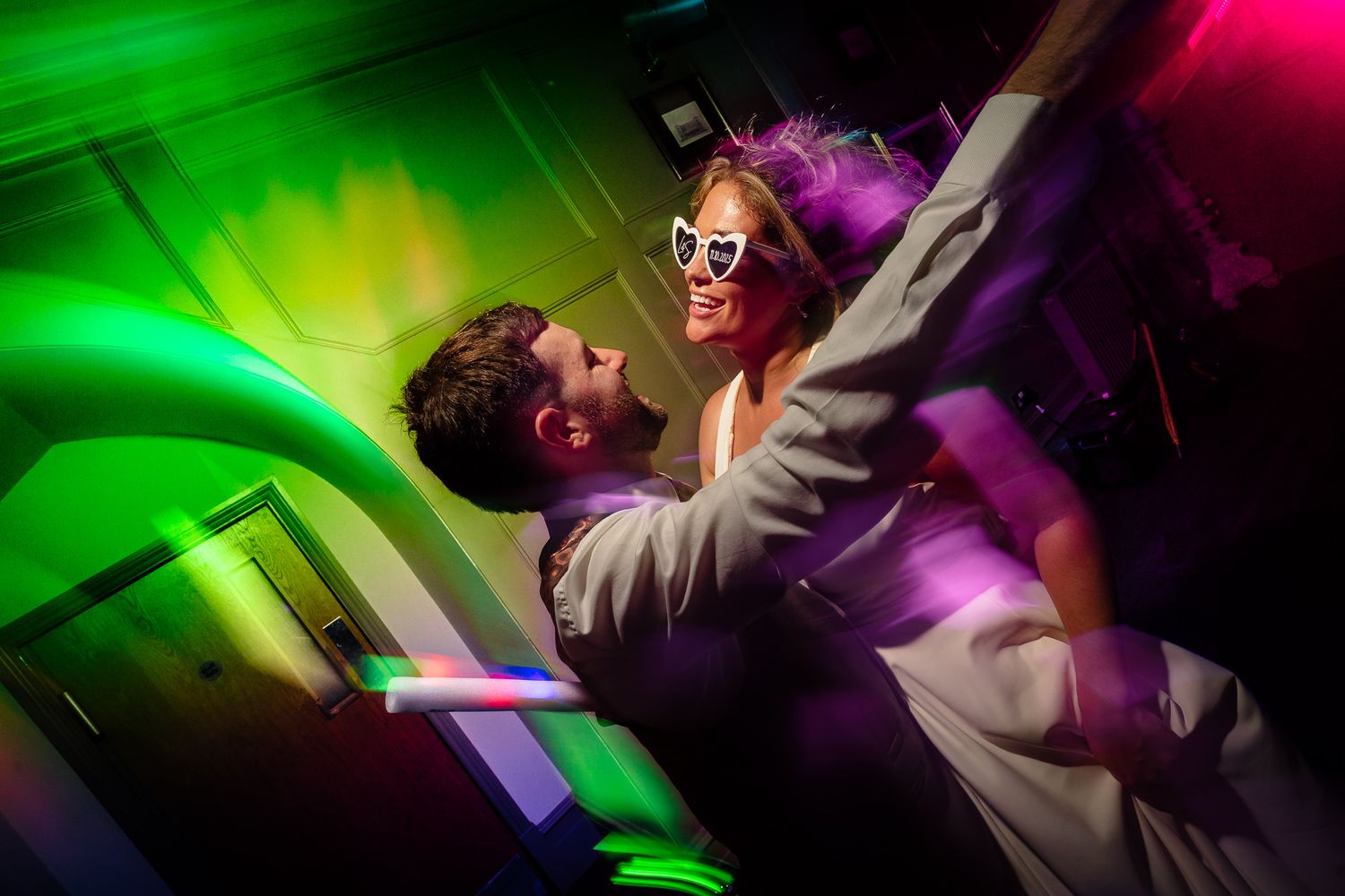 Dynamic wedding reception photos showing dancers silhouetted against bright green and pink lights.