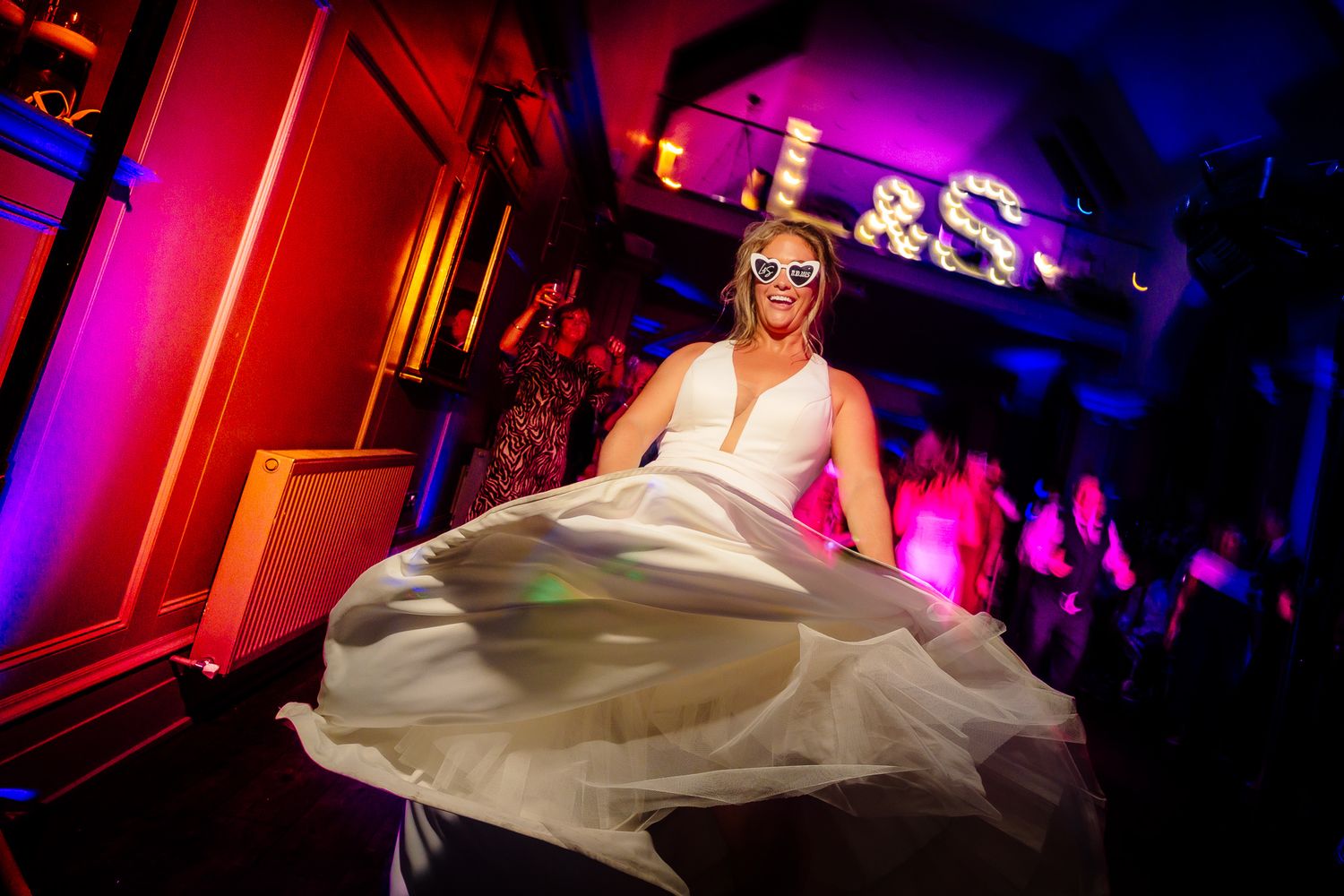 Wedding reception venue bathed in dramatic red and pink lighting creating a festive atmosphere.