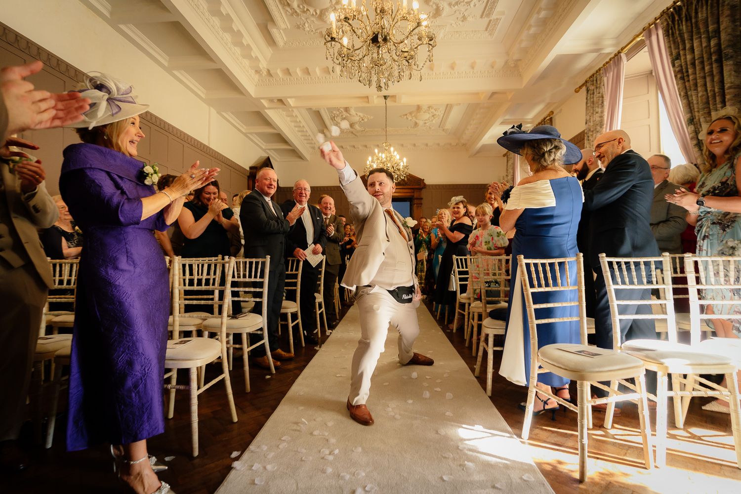 Wedding reception venue with elegant chandelier and white chairs set up for celebration.