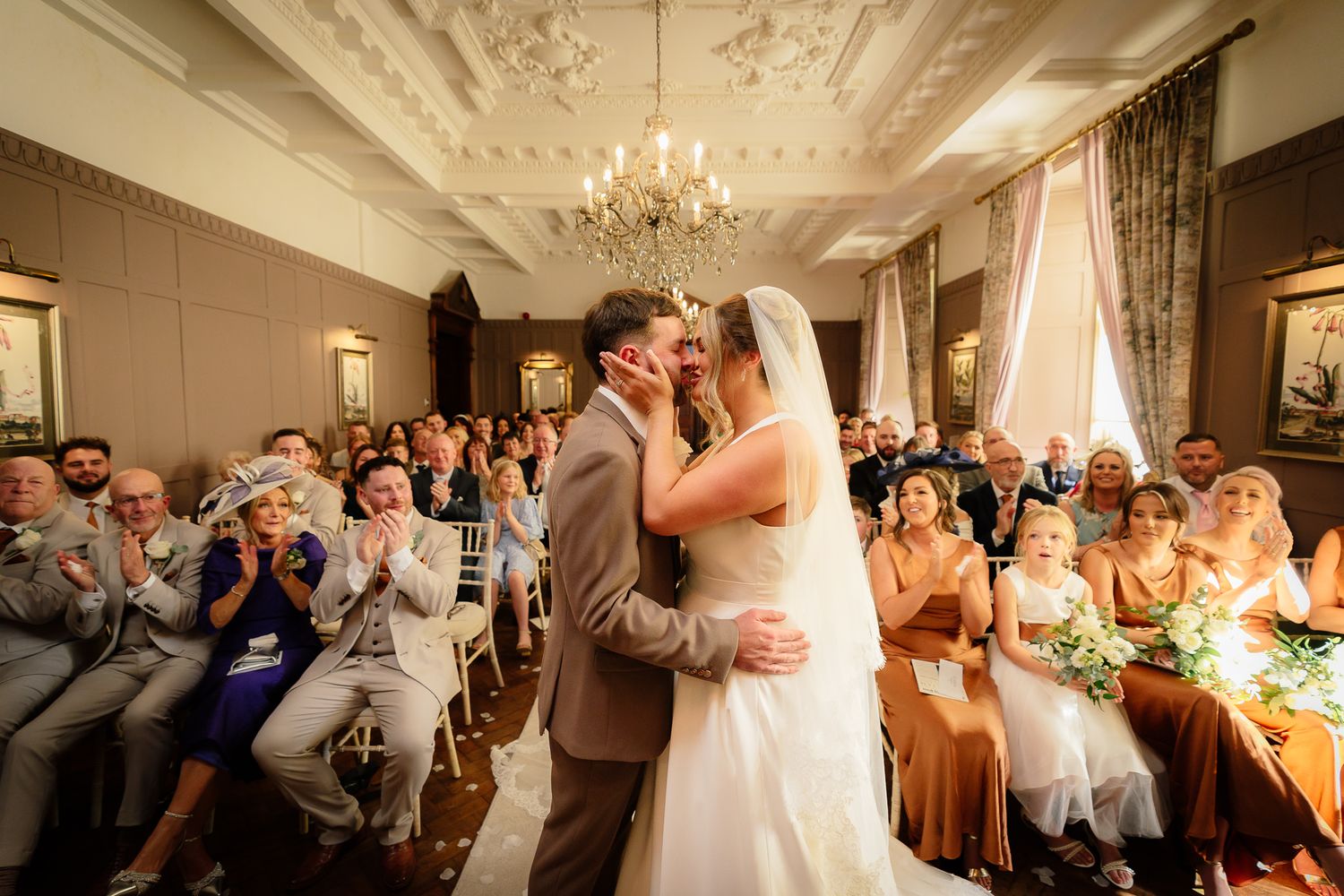 Wedding reception in an elegant ballroom with ornate ceiling and chandeliers.