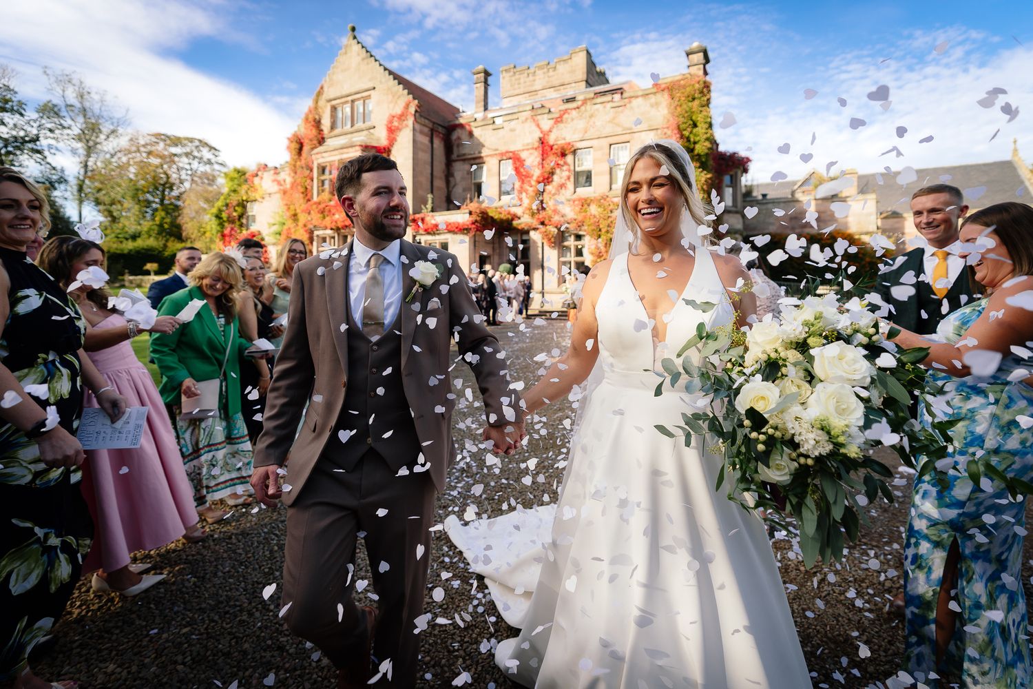 Wedding celebration with confetti being thrown outside a historic brick building.