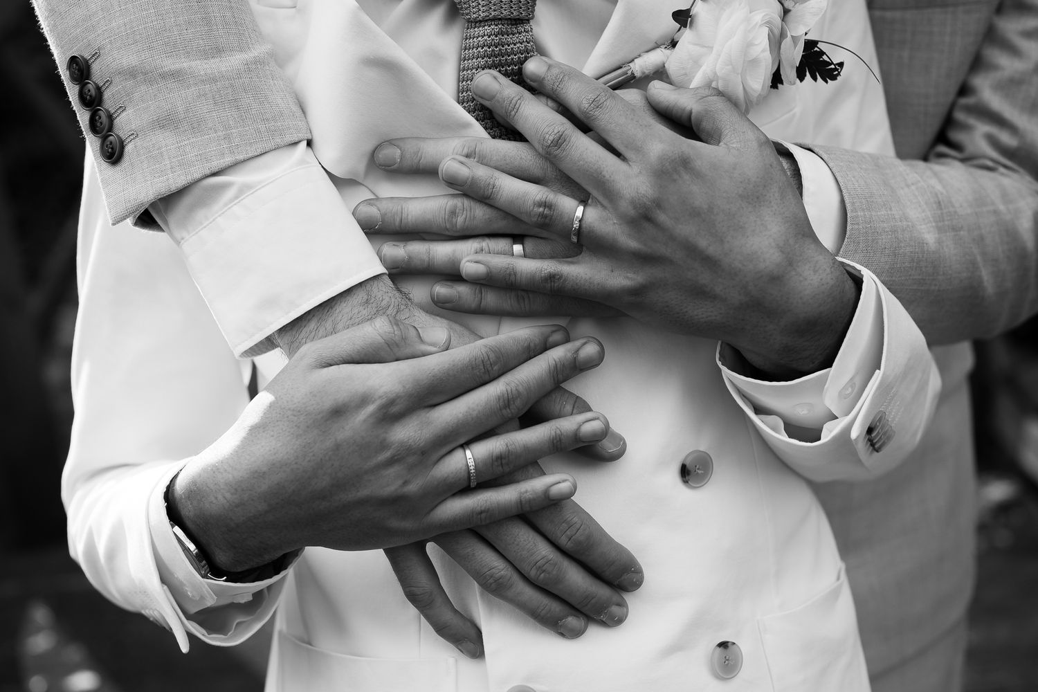 Close-up of hands showing wedding rings in black and white.