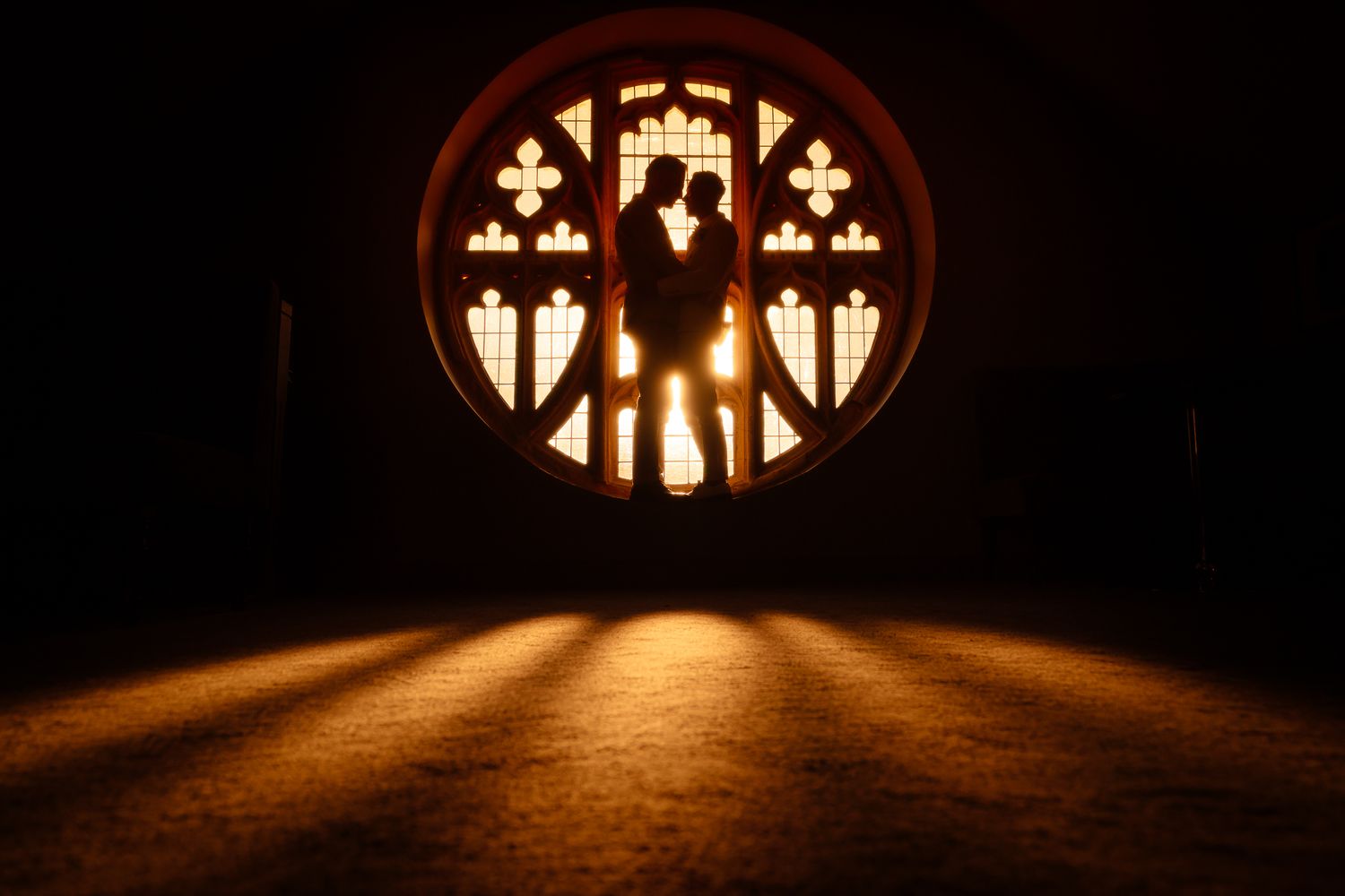 Dramatic silhouette of church windows casting warm light patterns on floor.