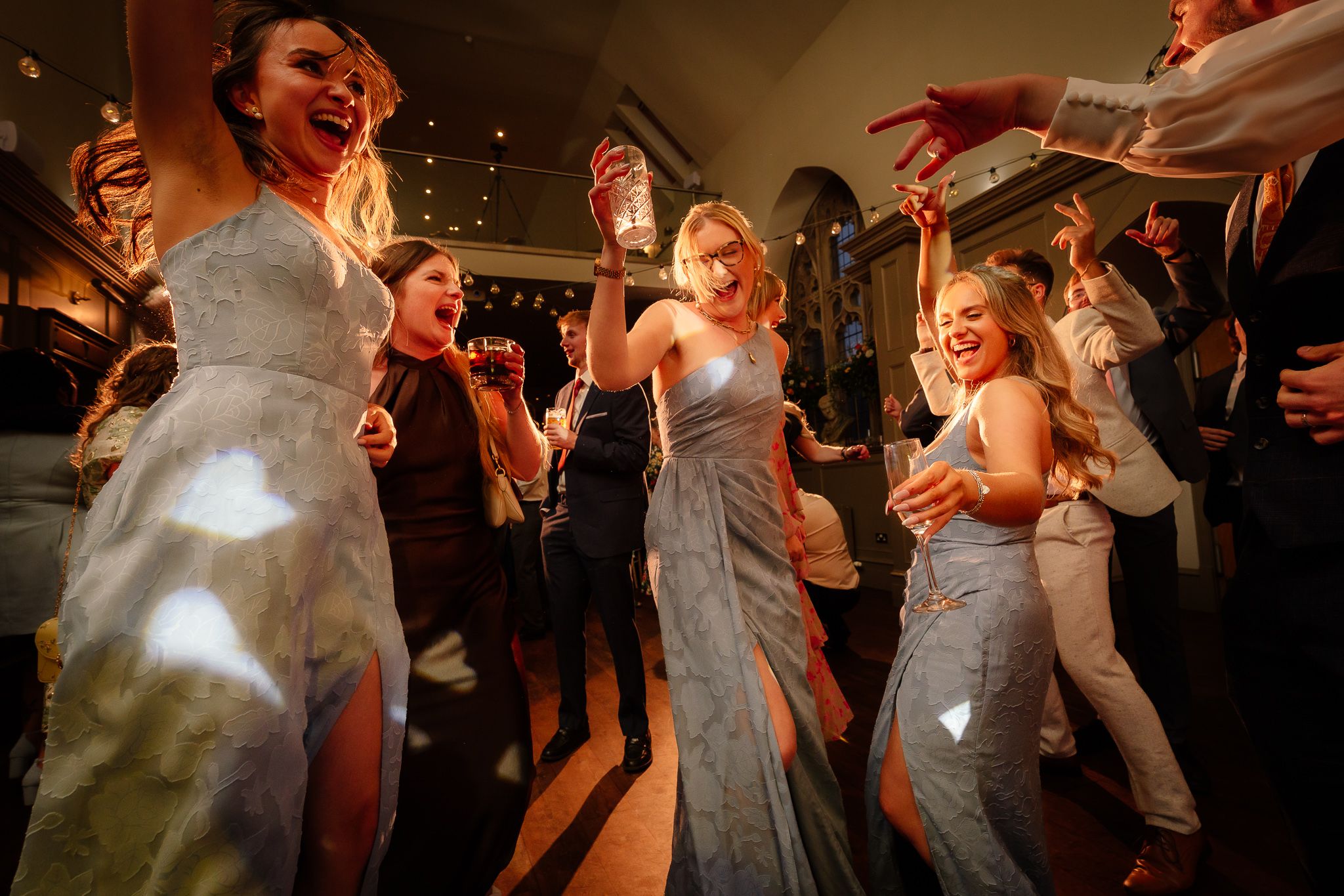 Wedding guests dancing and celebrating on a dimly lit dance floor. Ellingham Hall
