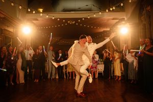 Wedding guests dancing energetically under warm string lights at an indoor reception celebration. Ellingham Hall