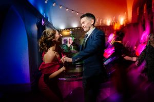 Wedding reception venue lit with dramatic red and blue lighting effects creating a club-like atmosphere. Ellingham Hall