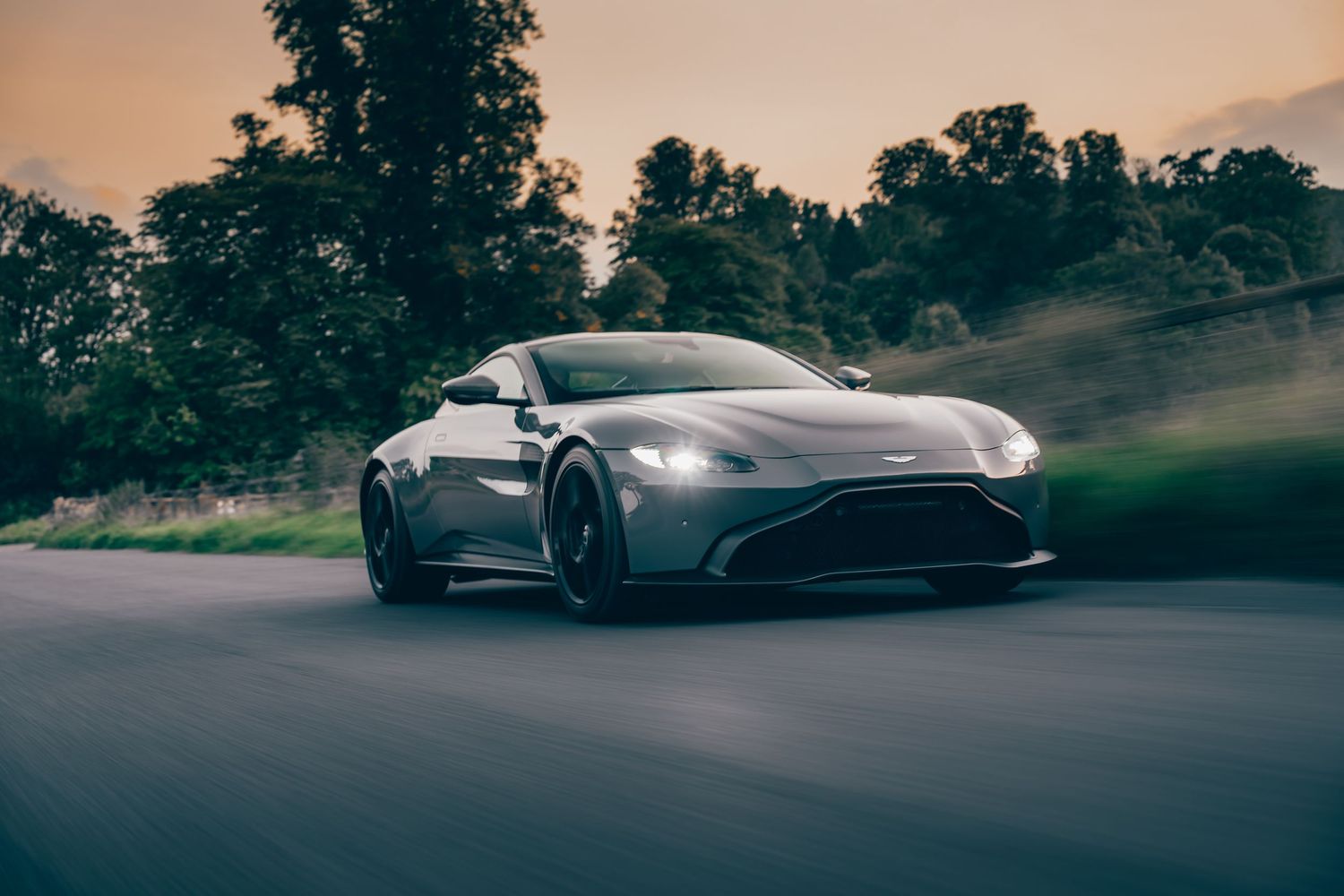 Silhouettes of luxury sports cars against a dramatic sunset sky.