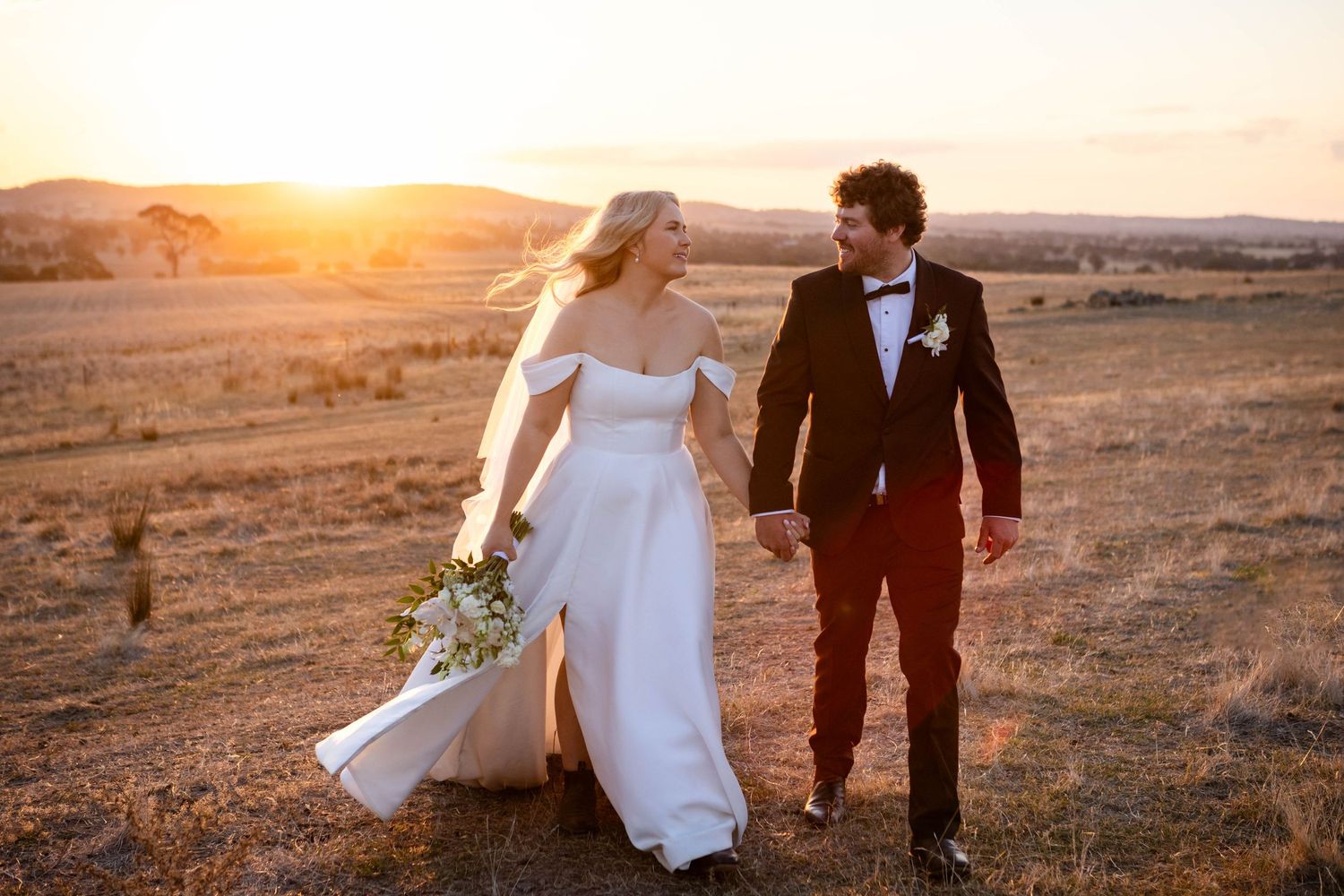 Romantic sunset wedding portraits in a golden field at magic hour.