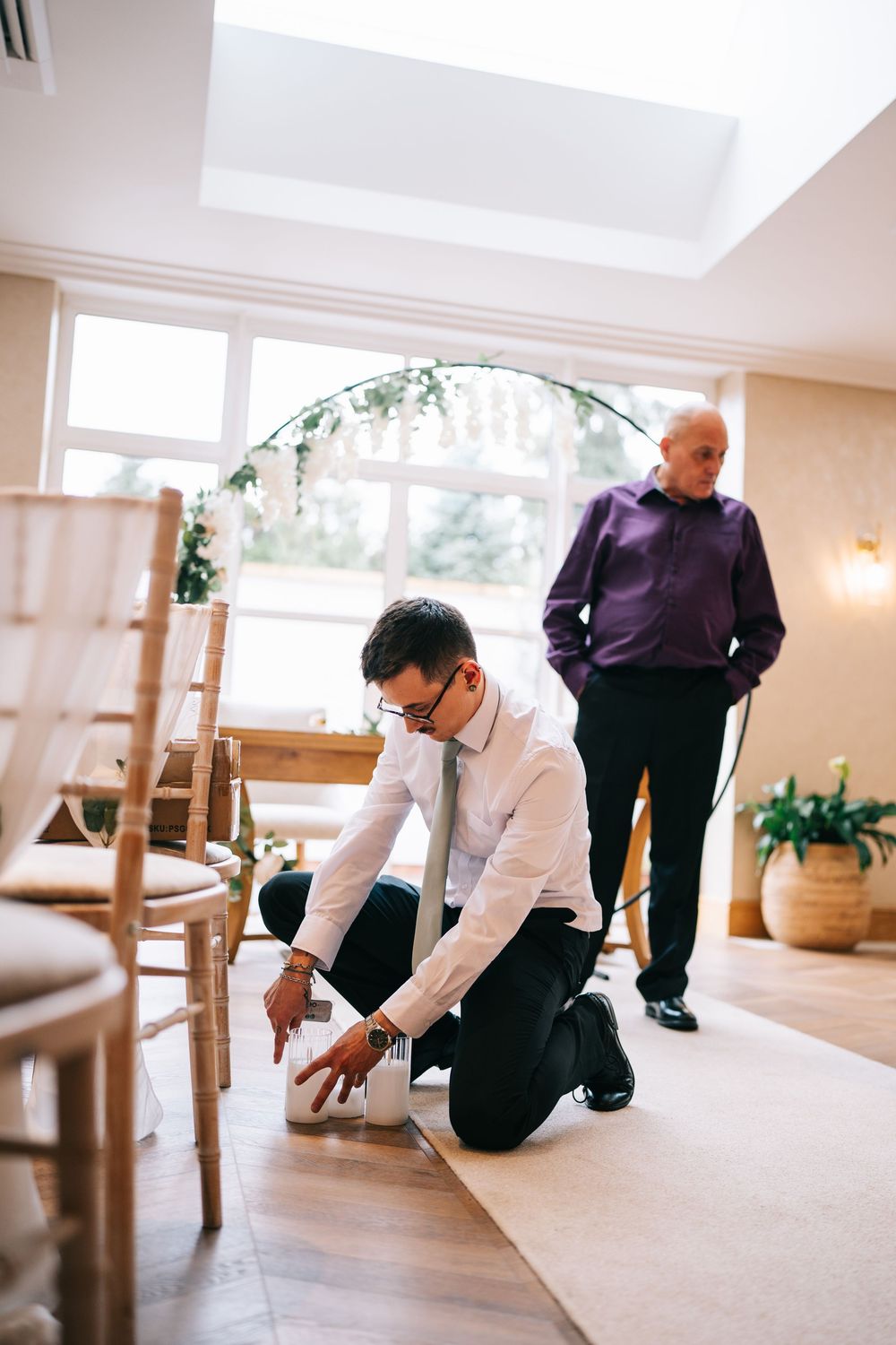 Groomsmen decorate at an indoor wedding reception venue.