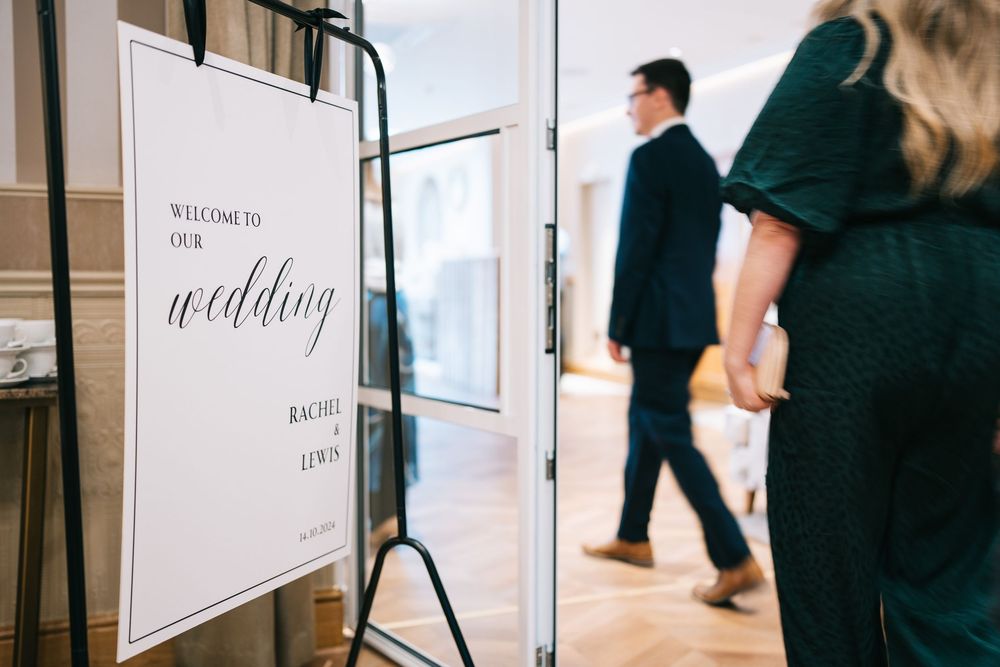 Black and white wedding signage displayed at an elegant indoor venue entrance.