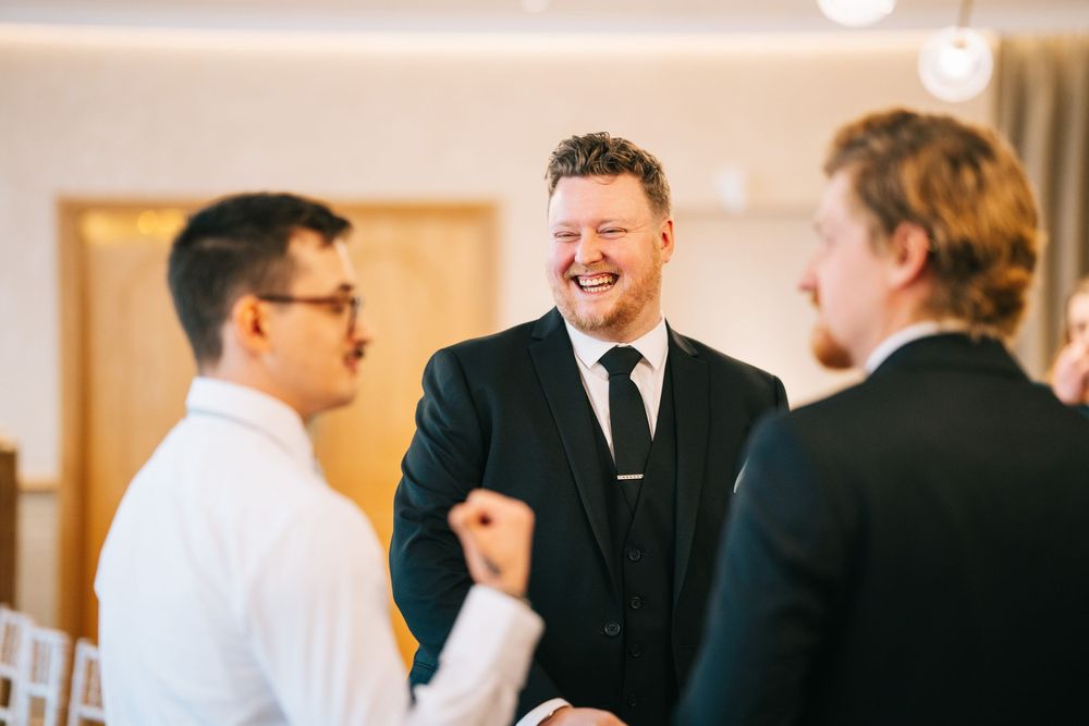 Wedding guests laugh and celebrate during a joyful reception moment.