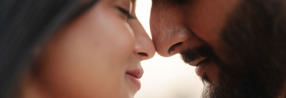 A romantic couple shares an intimate moment in a close-up portrait with warm lighting and soft focus.