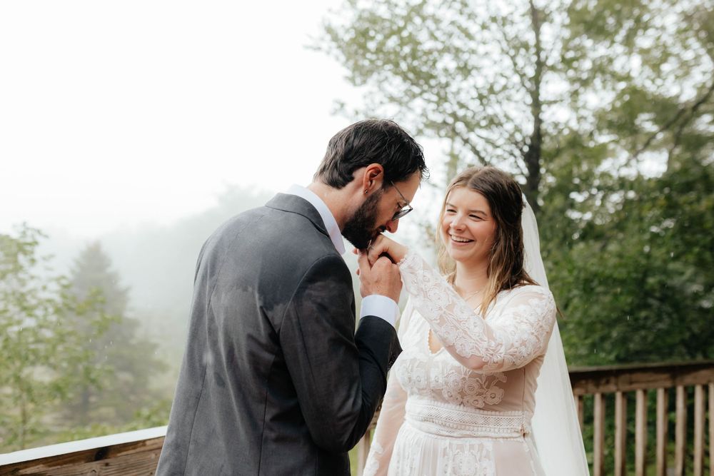 A couple shares an intimate moment on a misty mountain overlook during their wedding celebration.