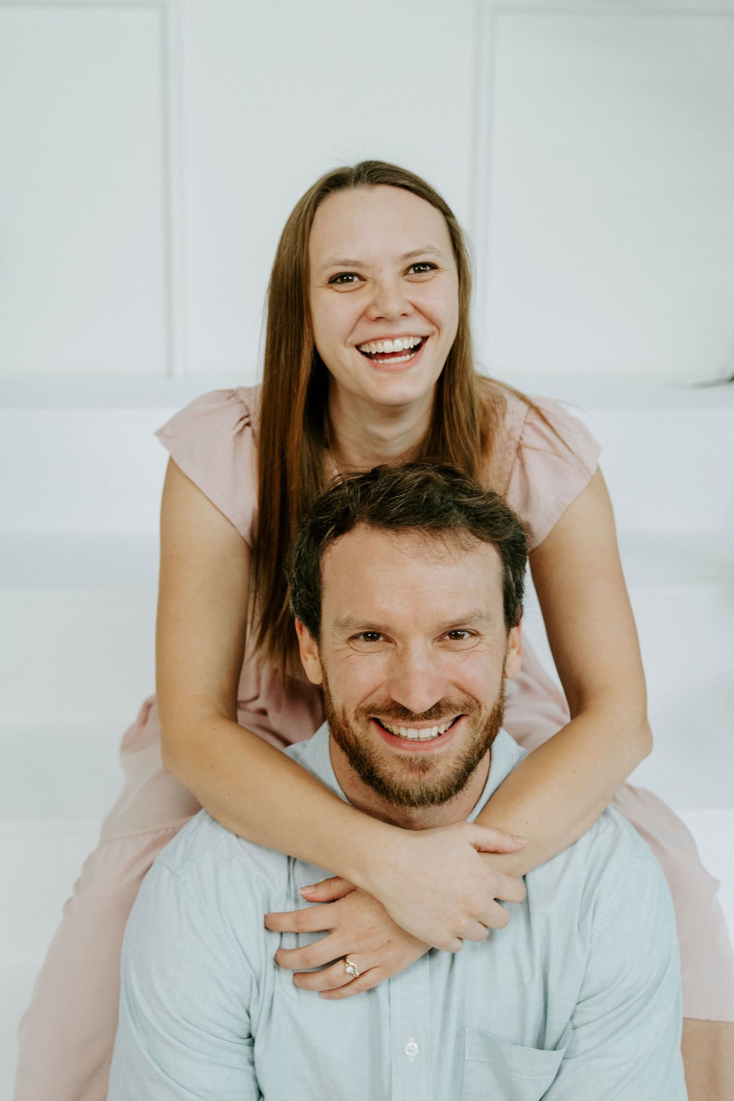 Playful couple portrait series against white backdrop showing intimate moments and laughter.