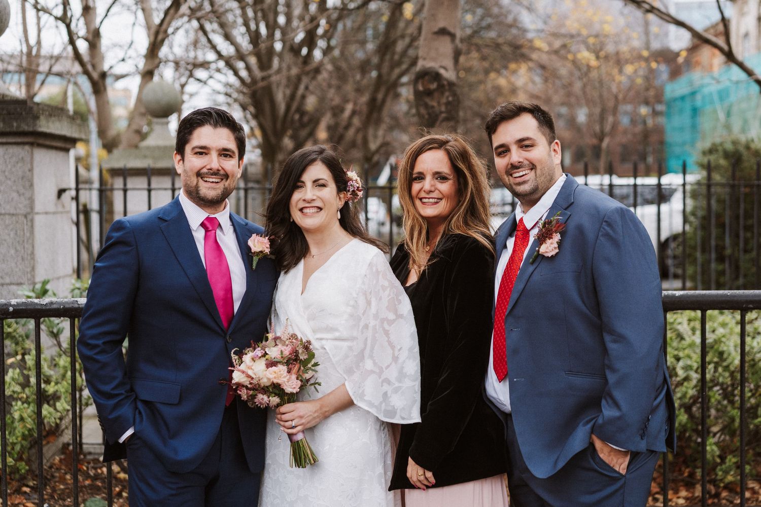Wedding party poses together outdoors in winter with bridesmaids in burgundy dresses and groomsmen in navy suits.