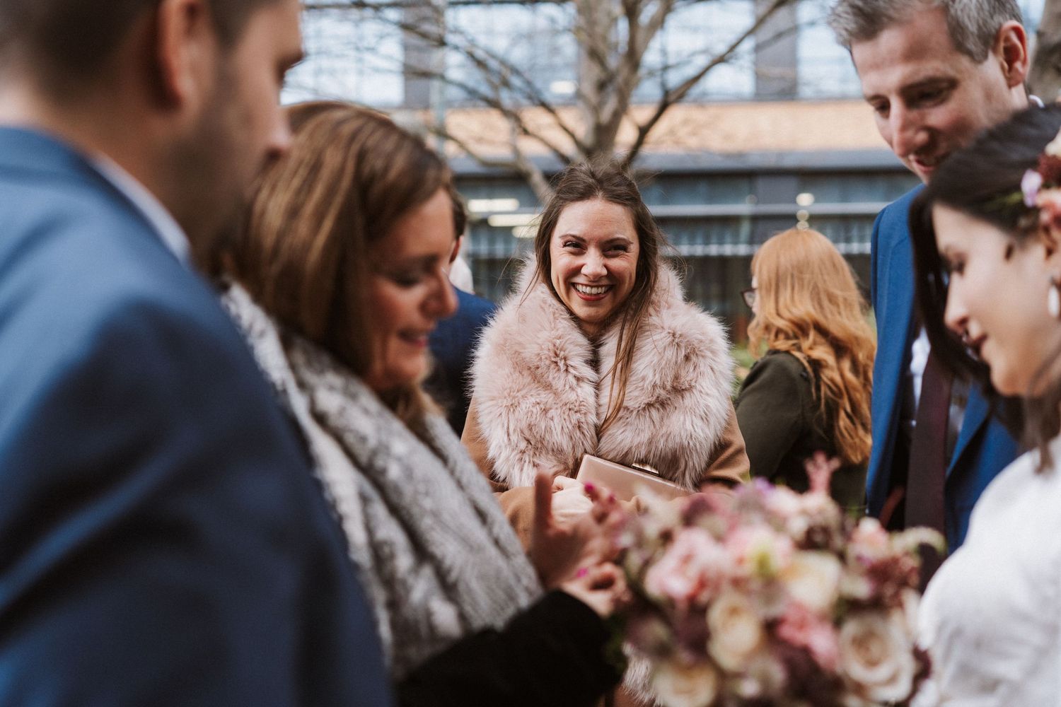 Group of wedding guests enjoying an outdoor celebration with laughter and smiles during a daytime reception.