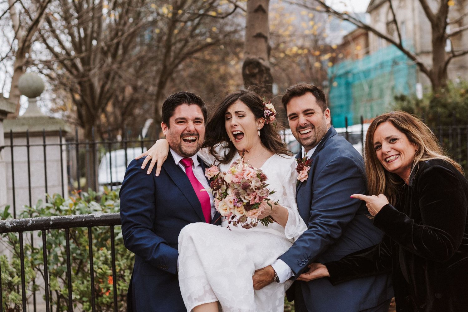 Group of wedding guests sharing joyful laughter together outdoors during a celebration.