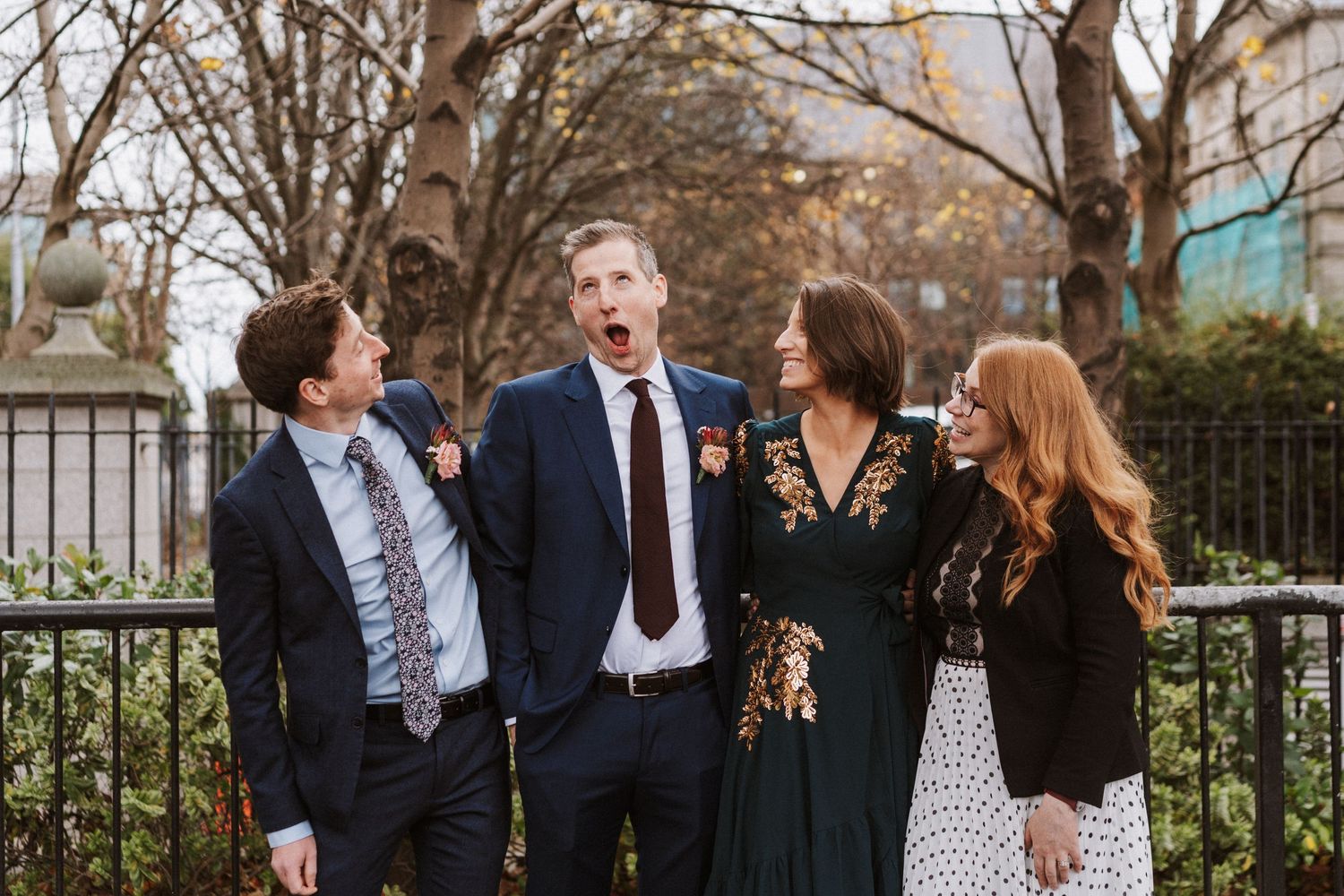 Wedding party members enjoying candid moments and conversation in an outdoor garden setting.
