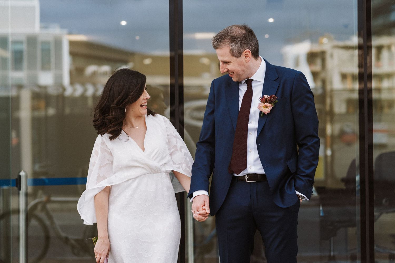 A couple in wedding attire share a tender moment while walking together outdoors.