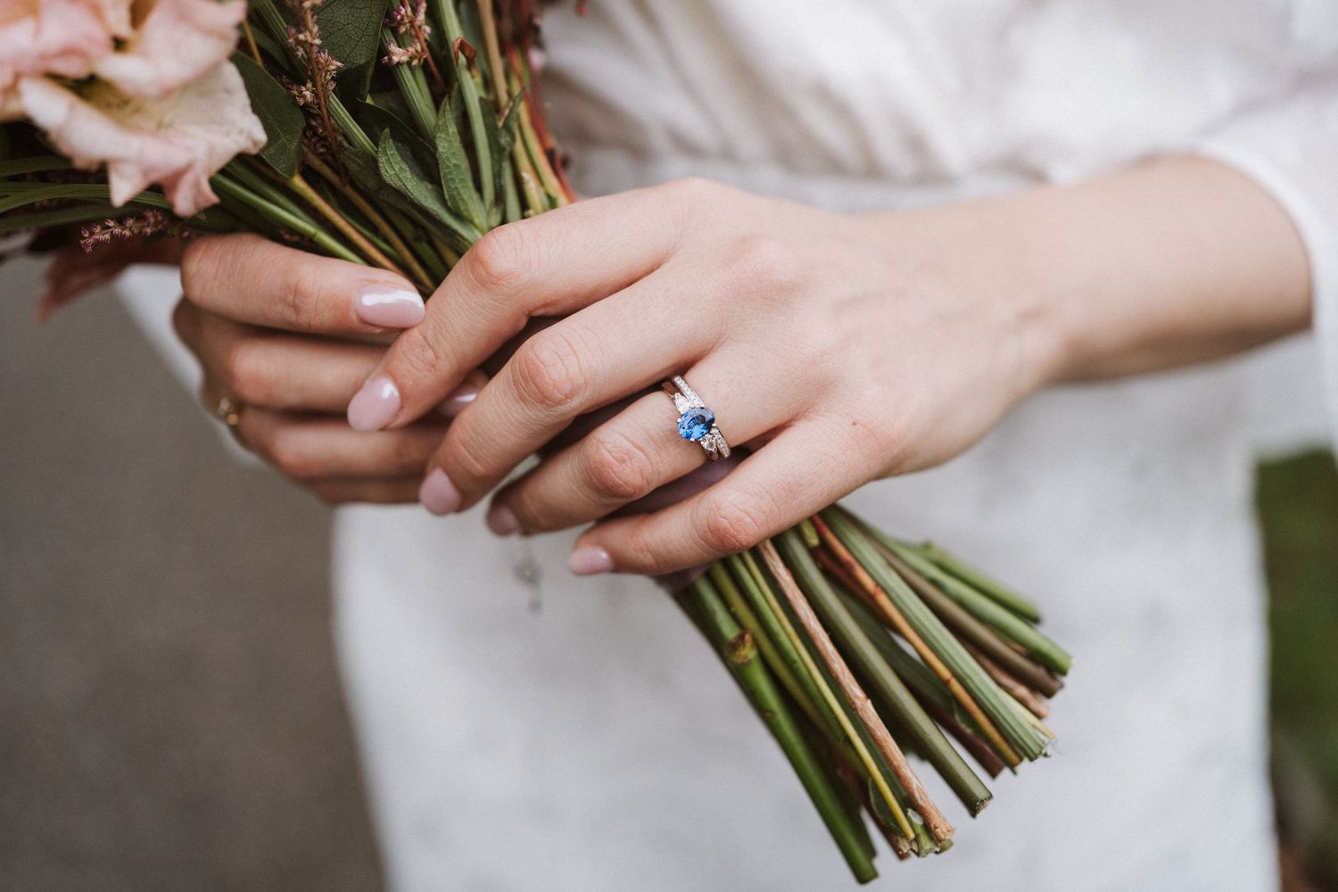 Close-up detail shots of wedding bouquet and engagement ring with white lace dress details.