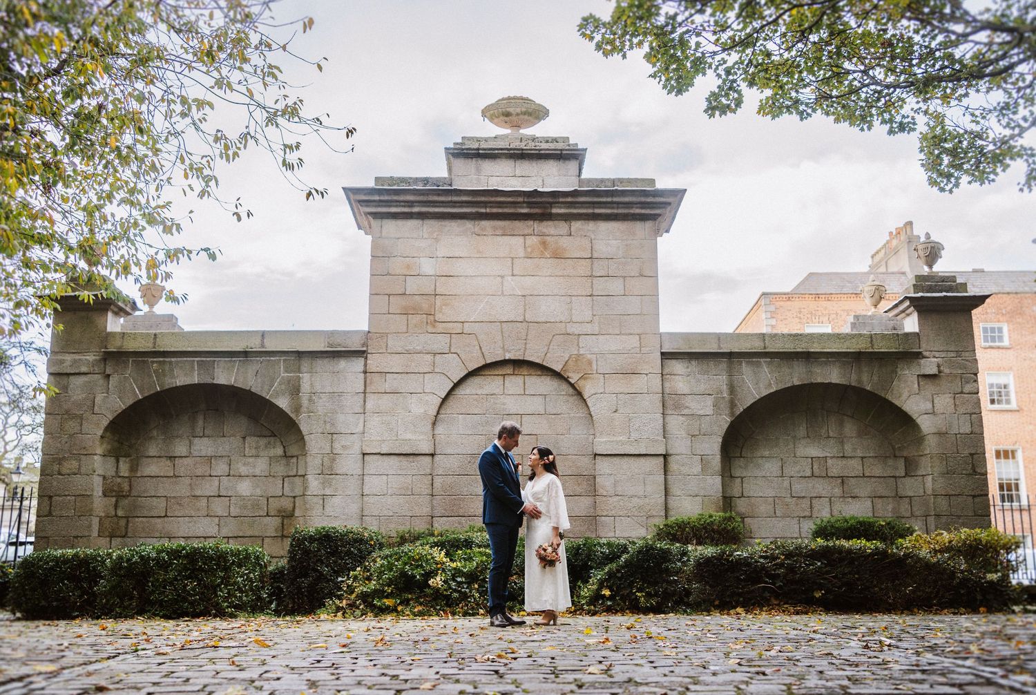 A stone wall archway at a wedding venue creates a romantic backdrop for an elegant outdoor ceremony.