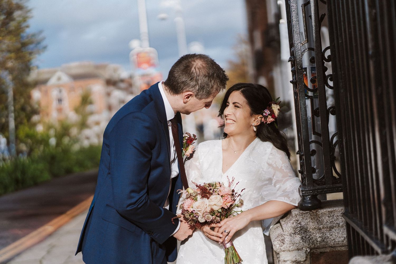 A couple shares a romantic moment together in formal wedding attire on a path lined with iron gates.