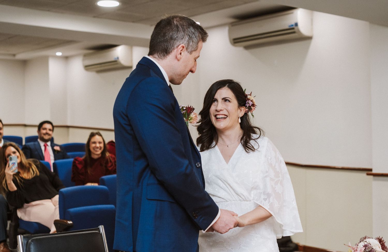 Candid moments captured during a wedding reception in a white-walled venue with navy blue decor accents.
