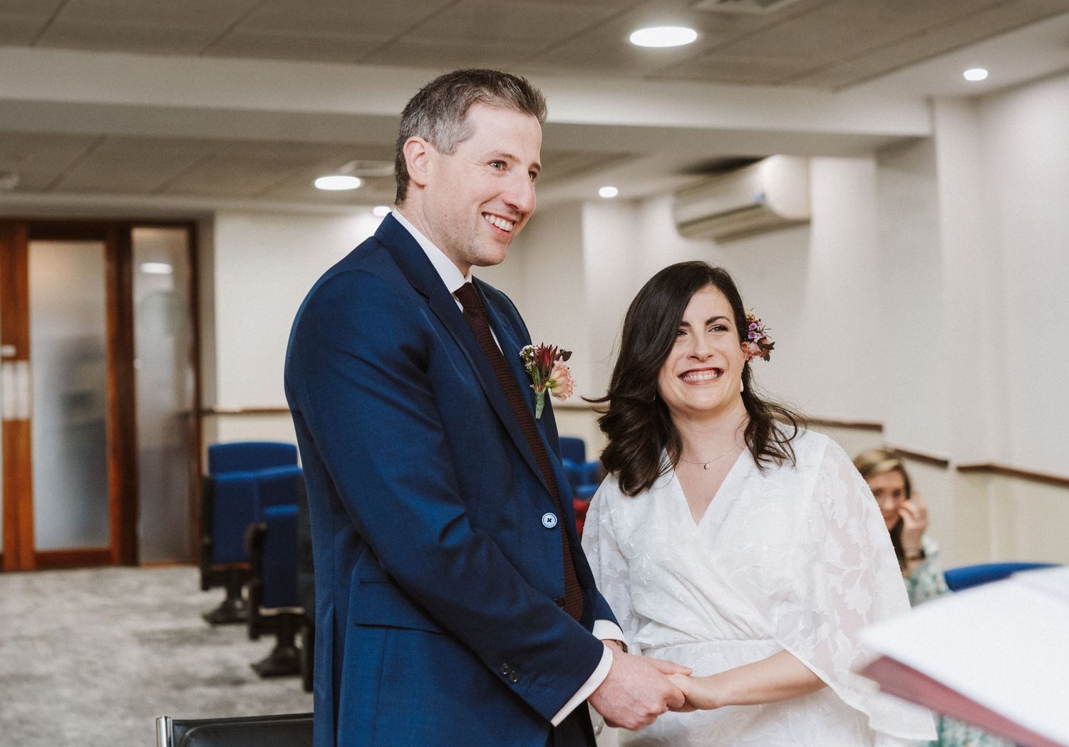 Couple shares a joyful moment together in a bright indoor venue wearing formal attire.