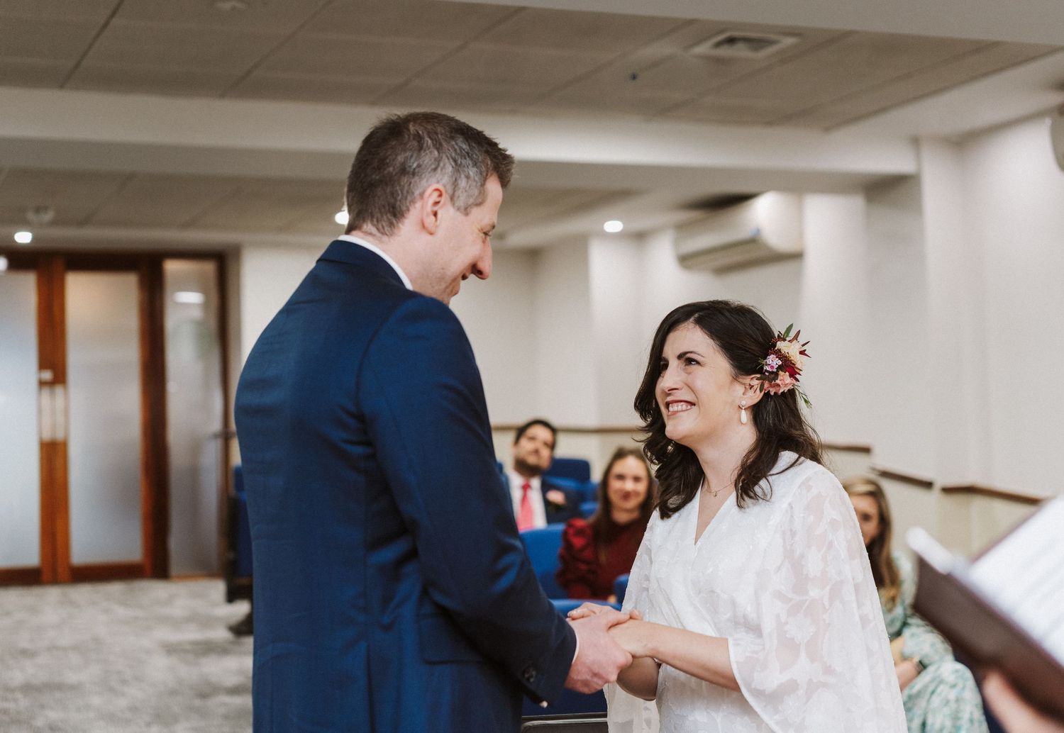 A couple shares a joyful moment during their wedding ceremony in a bright indoor venue.