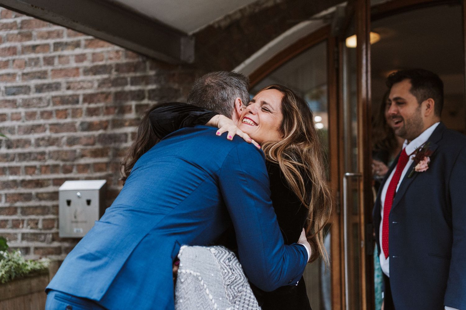 A couple shares a romantic dance moment during their wedding celebration in a rustic brick venue setting.