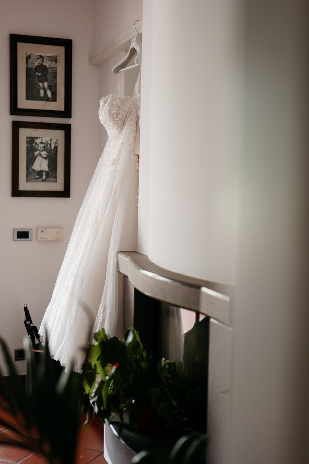 White wedding dresses hanging on display in a room with framed photos on the wall.