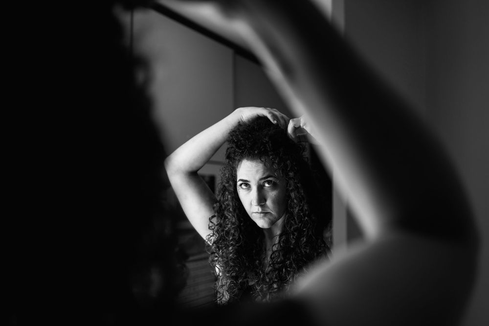 Artistic black and white portrait showing curly hair and dramatic lighting.