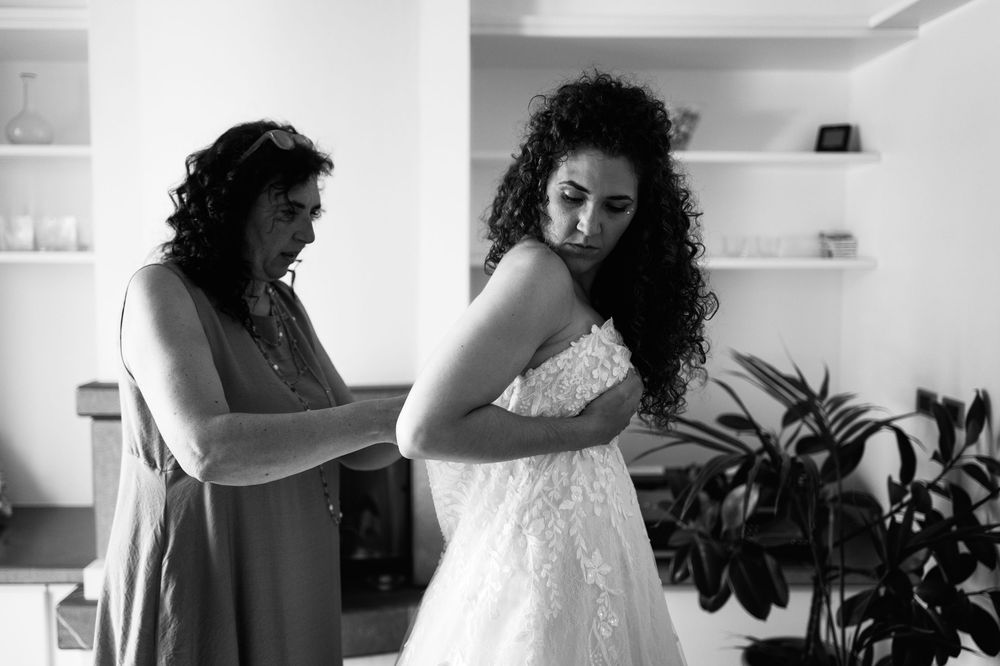 Black and white photo showing final adjustments being made to a wedding dress.