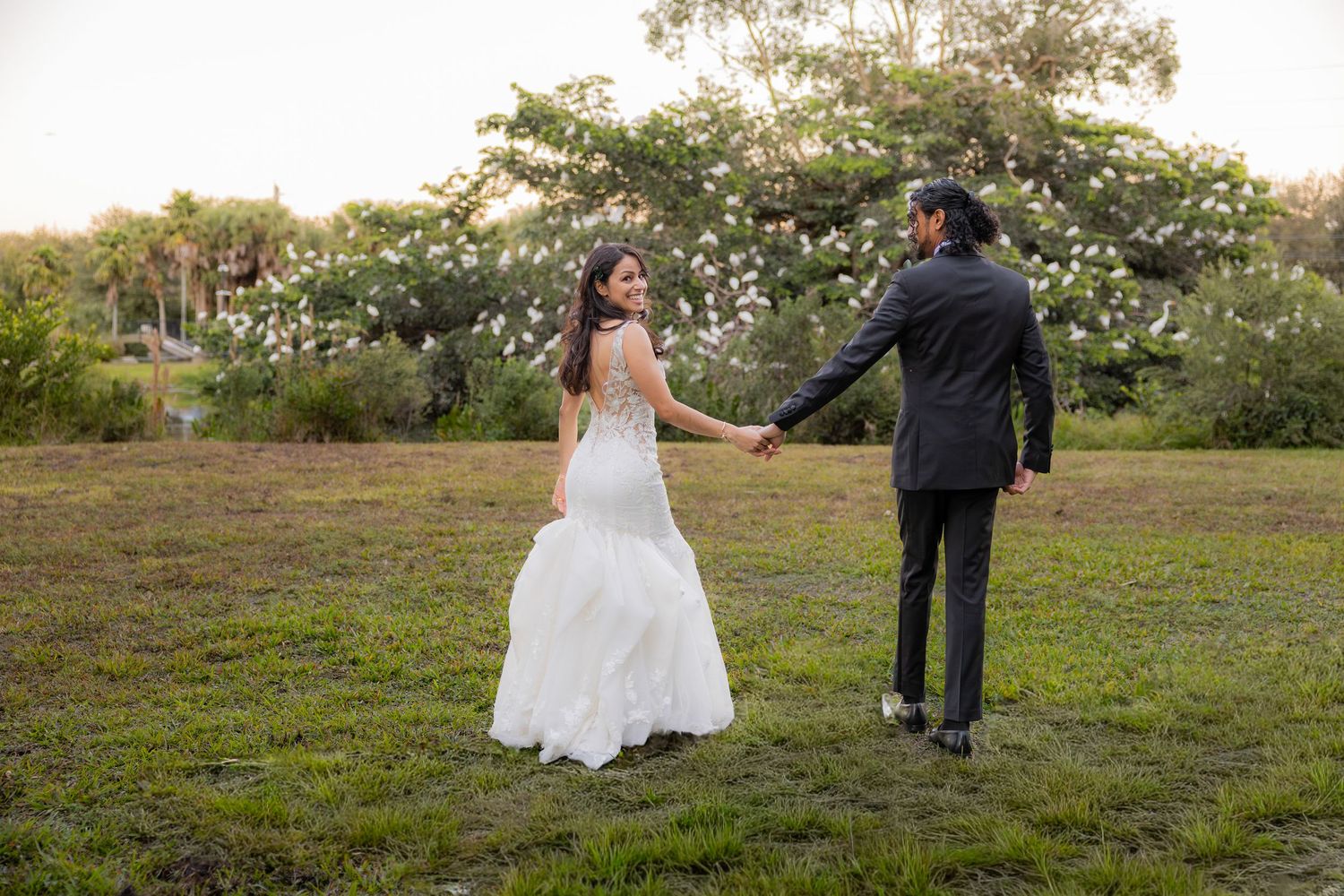 Bride and Groom holdings hands walking through field at Long Key Natural Area & Nature Center