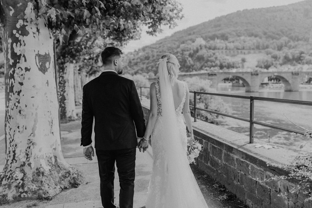 Brautpaar läuft am Hochzeitstag Hand in Hand am Necker entlang Richtung Alte Brücke