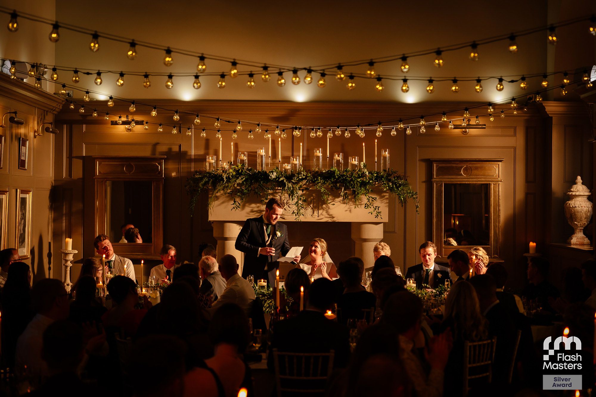 Wedding reception venue decorated with warm string lights and elegant table settings creating a romantic atmosphere.