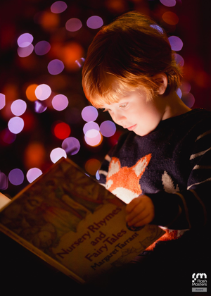Child reading a book illuminated by magical bokeh lights in warm colors.